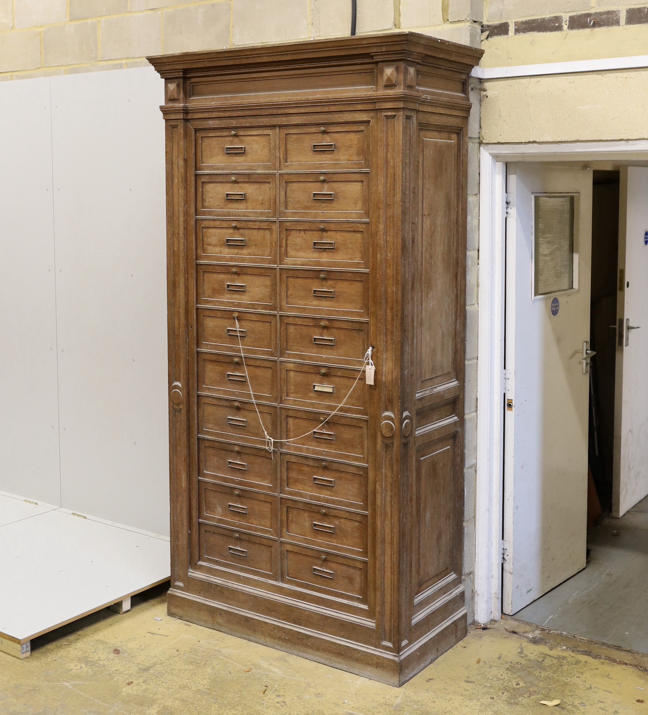 An early 20th century French oak notaries cabinet with twenty fall front compartments, width 125cm, depth 60cm, height 240cm